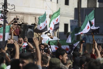 Thousands of Syrians march in Idlib carrying the Syrian revolutionary flag during a protest against