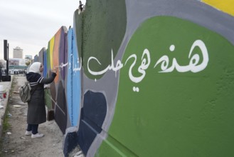 Young volunteers paint murals on walls to decorate the city following the fall of Bashar al-Assad's