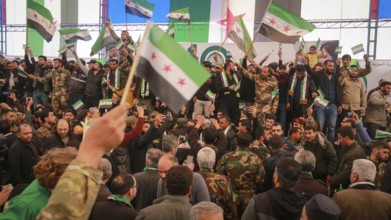 Syrians are seen demonstrating against the rule of Bashar al-Assad while carrying banners and the