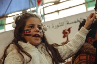 Syrians are seen demonstrating against the rule of Bashar al-Assad while carrying banners and the