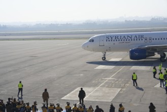 Syrians gather to welcome the first passenger plane to land at Aleppo International Airport
