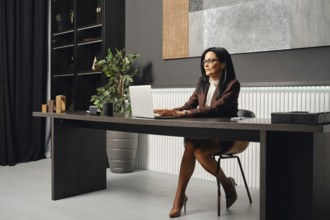 A business professional typing a report on her laptop while seated at a sleek desk in a