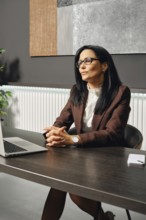 A serious female divorce lawyer listens to her interlocutor with a smile over a video link. She