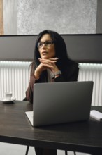 A divorce lawyer ponders strategy while sitting at a table in a modern office
