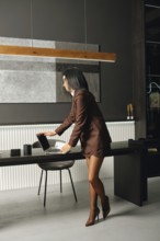 A confident professional woman in formal attire arranges her laptop on a sleek desk in a stylish