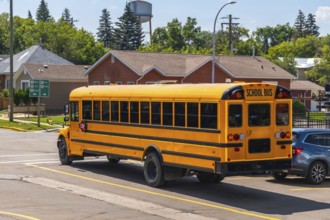 Yellow school bus driving down a suburban street during the daytime, transporting students to or