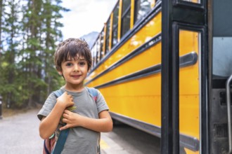 Elementary school student waiting at a mountain road, carrying a backpack and anticipating the