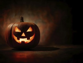 A spooky carved glowing pumpkin in a dark room, symbolising Halloween and autumnal mood, AI