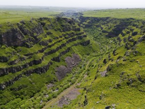 Deep gorge with lush green vegetation between steep rocks under a wide sky, aerial view, Kassagh