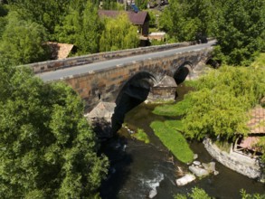 Aerial view of an old stone bridge over a winding river in green nature, aerial view, bridge from