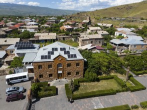 Aerial view of a village with a building with solar panels and surrounding hills, aerial view,