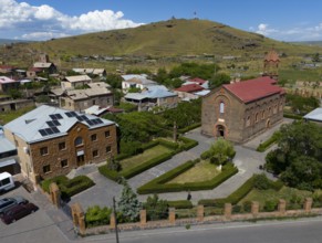 Aerial view of a village with a church and a hill in the background under a blue sky, aerial view,