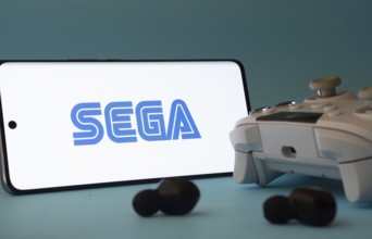 Dhaka, Bangladesh- 13 Sep 2025: A smartphone with the Sega icon next to a controller and earbuds on
