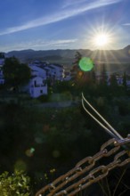 Steel cables and chains stretch towards the picturesque town of ronda, spain, bathed in the golden