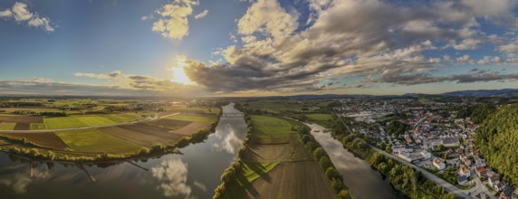 The sunset bathes the river landscape of the Danube in a warm light. A few fields and meadows