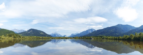 Panoramic lake reflects the surrounding mountains and the slightly cloudy sky, Admont, Styria,