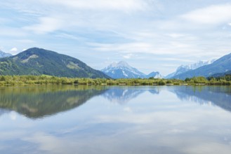 Panoramic lake reflects the surrounding mountains and the slightly cloudy sky, Admont, Styria,