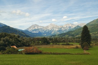 Wide meadows stretch out in front of an alpine mountain range, Haller Mauern, under a clear sky,