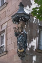 House saint, Mary with the baby Jesus under a canopy, at a residential and commercial building,