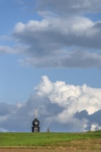 Tower of a chapel behind a meadow hill, cloudy sky, Köttweinsdorf, Upper Franconia, Bavaria,