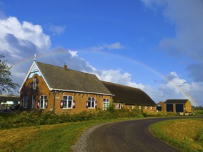 A picturesque farm in the countryside with a rainbow over the blue sky, former monastery, farm with