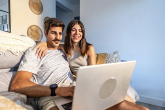 Young couple enjoying a streaming movie on a laptop, relaxing together on a comfortable sofa in