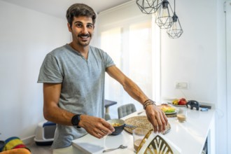 Happy man preparing a nutritious breakfast in a bright, modern kitchen, enjoying a relaxed morning
