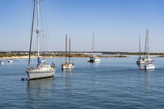 Sailboats anchored in the Gilão River, in front of the beach Praia da Ilha de Tavira, on the island