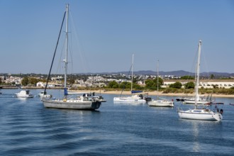 Sailboats anchored in the Gilão River, in front of the beach Praia da Ilha de Tavira, on the island
