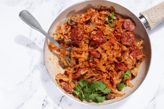 Bigos, Polish dish bigos, on a marble table, stewed meat with cabbage, chorizo sausages, mushrooms,