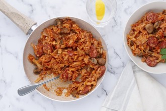 Bigos, Polish dish bigos, on the table, pan with stewed meat, with cabbage, chorizo sausages,
