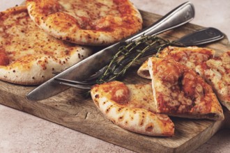 Four pizzetta Margaritas, on a cutting board, on a light gray surface, top view