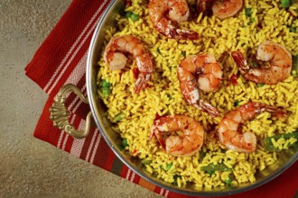 Rice with saffron and shrimp, in a frying pan, paella with shrimp, top view, homemade, no people
