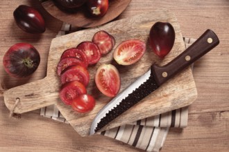 Sliced tomatoes, Black Beauty variety, on a cutting board, top view, on the kitchen table