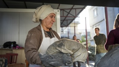 A Turkish woman bakes traditional bread on a clay tandoor oven in a rural village, Hatay, Hatay,