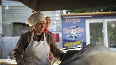 A Turkish woman bakes traditional bread on a clay tandoor oven in a rural village, Hatay, Hatay,