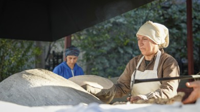 A Turkish woman bakes traditional bread on a clay tandoor oven in a rural village, Hatay, Hatay,