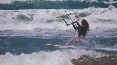 Woman kitesurfing energetically over waves in sunny sea environment, Prasonisi, beach, surf,