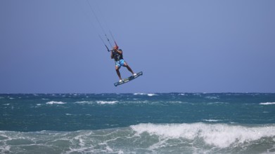 Kitesurfer jumping high over waves under a clear blue sky, Prasonisi, beach, surf, windsurfer, kite
