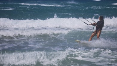 Kitesurfer gliding through moving waves in the ocean under blue sky, Prasonisi, beach, surf,