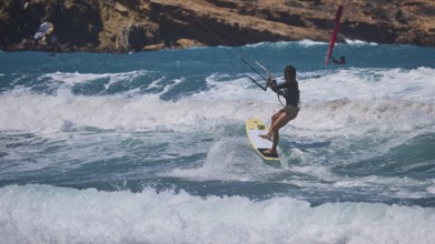 Kitesurfer skilfully navigates the waves off the rocky coast, Prasonisi, beach, surf, windsurfer,