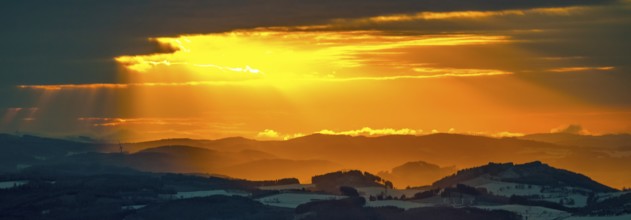 Aerial view of the sunset with a view over the snowy winter landscape from Winterberg to the