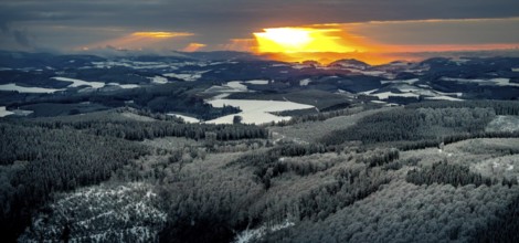 Aerial view of the sunset with a view over the snowy winter landscape from Winterberg to the