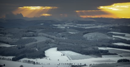 Aerial view of the sunset with a view over the snowy winter landscape from Winterberg to the