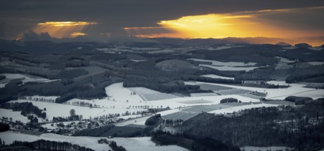 Aerial view of the sunset with a view over the snowy winter landscape from Winterberg to the