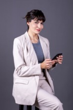 Elegant professional businesswoman holding her phone while looking at camera