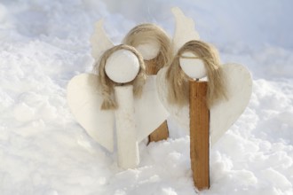 Homemade decorative angels made of wood and plaster in the snow