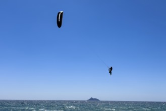Kitesurfer kite surfer makes big high giant jump with kite kite sail over sea surface,
