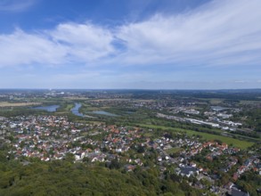 View of a town with river and green landscape under a blue sky with clouds, aerial view from the
