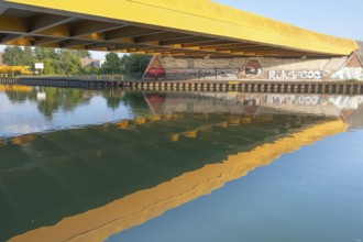 View across the Mittelland Canal to the underside and the graffiti-painted abutment of a bridge on